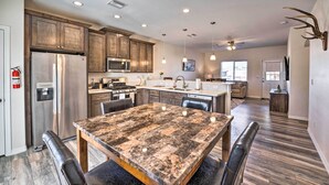 Une cuisine spacieuse dotée de meubles en bois, d’un réfrigérateur en acier inoxydable et d’un grand îlot central avec des places assises.