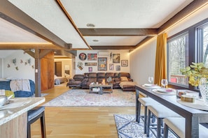 A spacious living room with a large sofa set, a dining area with a long table, and a kitchen area with a countertop and stools. - East Fishkill Escape, Close to Red Wing Park! (Hopewell Junction)