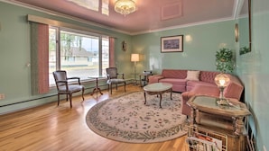 A living room with a round rug, wooden furniture, a chandelier, and a view through a window. - Nostalgic & Retro Anaconda Home, Walk to Town (Anaconda)