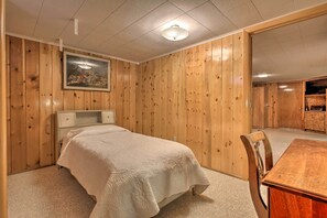 Een slaapkamer met een bed, een houten dressoir, een eettafel en een schilderij aan de muur.