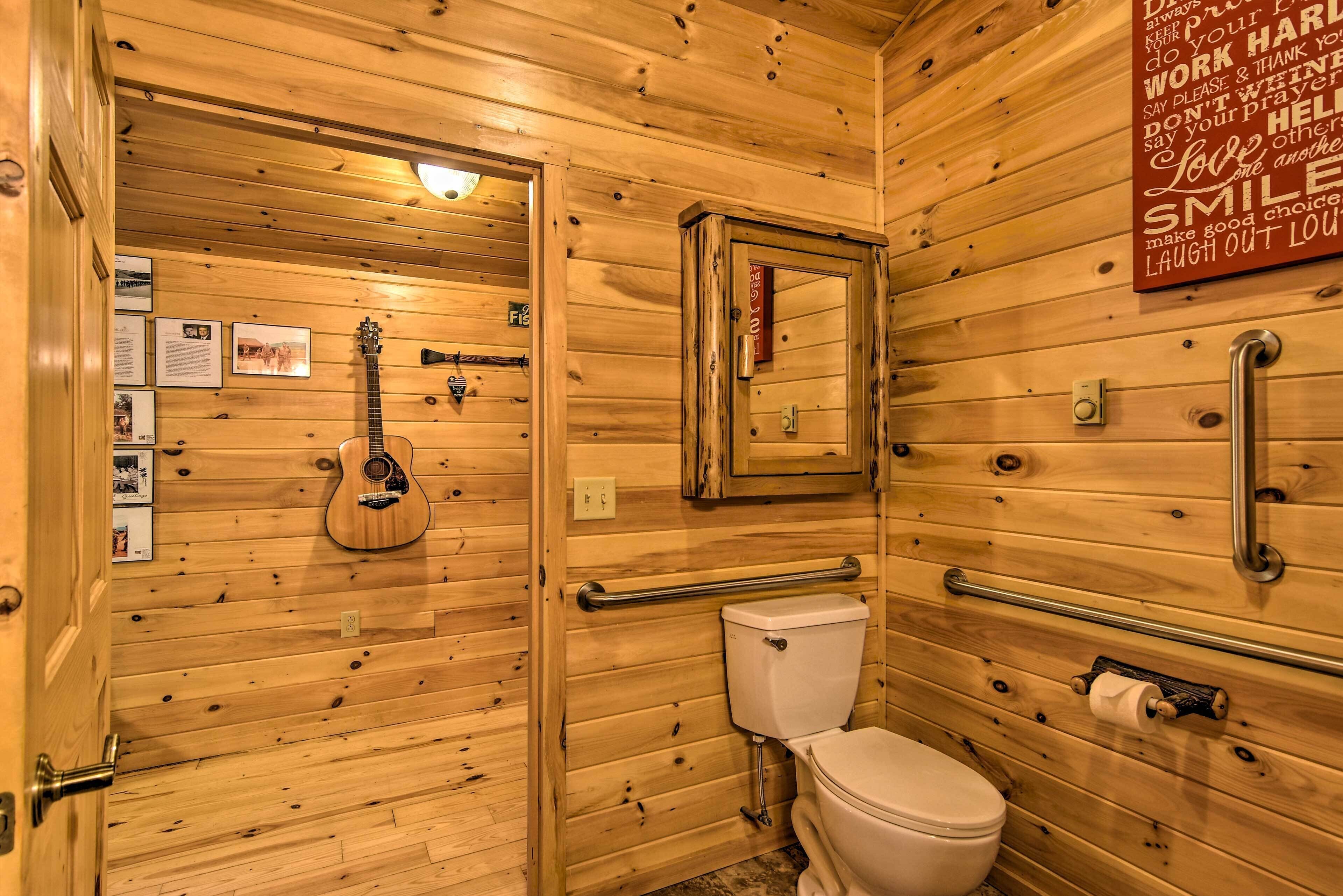 A wooden cabin bathroom with a toilet, a guitar, and a mirror.