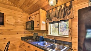 Cocina de cabaña de madera con un lavamanos doble, una tostadora y un refrigerador.