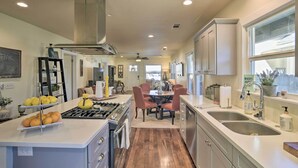 A modern kitchen with a central island, double sinks, and a dining area with red chairs. - Ideally Located Chico Home - Fire Pit & Grill (Chico)