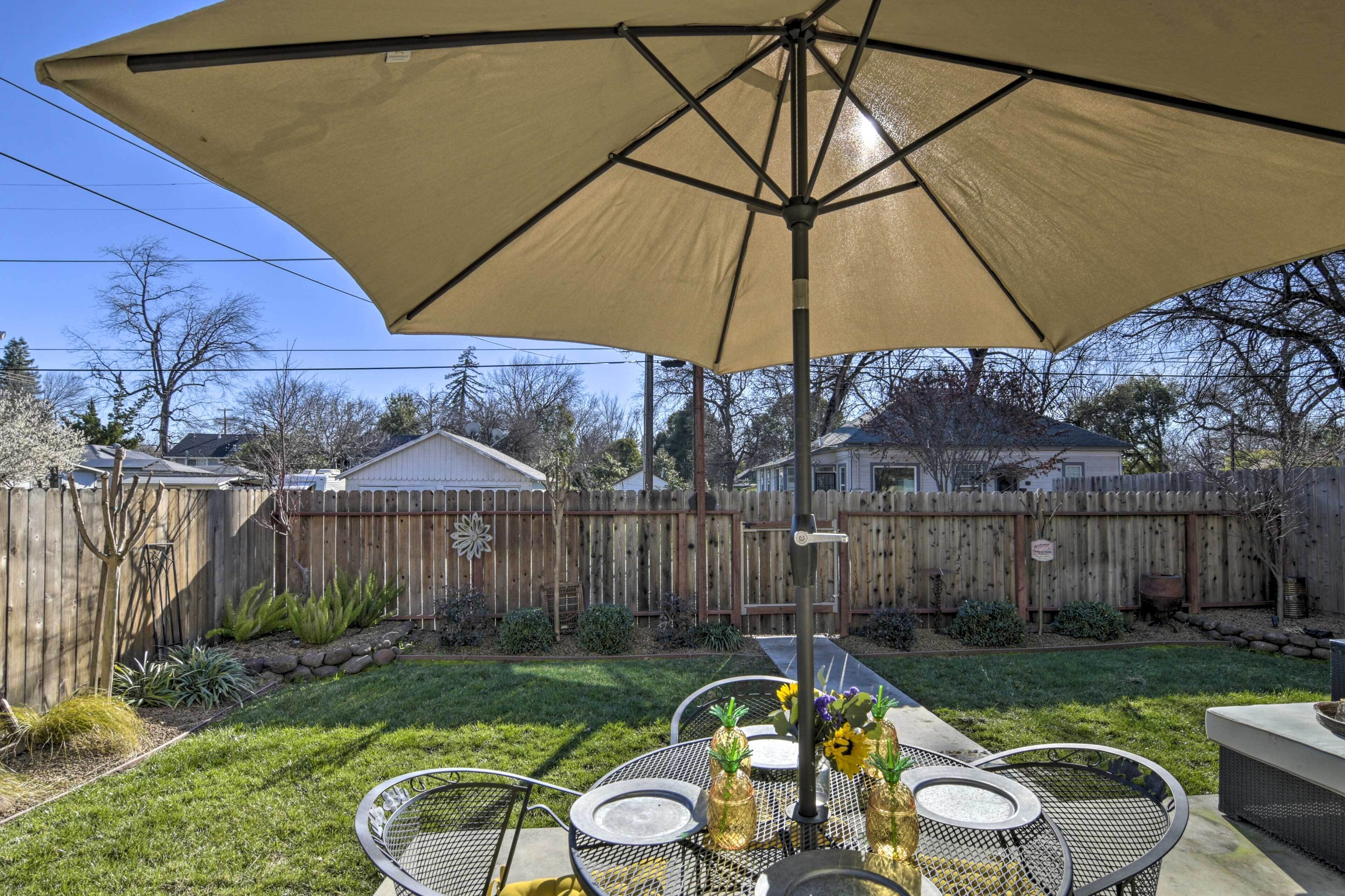 A backyard patio with a table, chairs, and an umbrella.