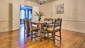 Un coin repas avec une table en bois, quatre chaises, un lustre, un vase décoré de plantes et un tableau accroché au mur.