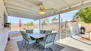 Une terrasse couverte avec une table et des chaises, un ventilateur de plafond et une vue sur le jardin arrière.