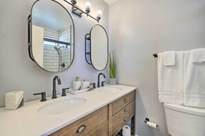 A bathroom with two sinks, a mirror, a towel rack, and a toilet. - Spacious Home w/ Pool & Grill in Phoenix! (Phoenix)