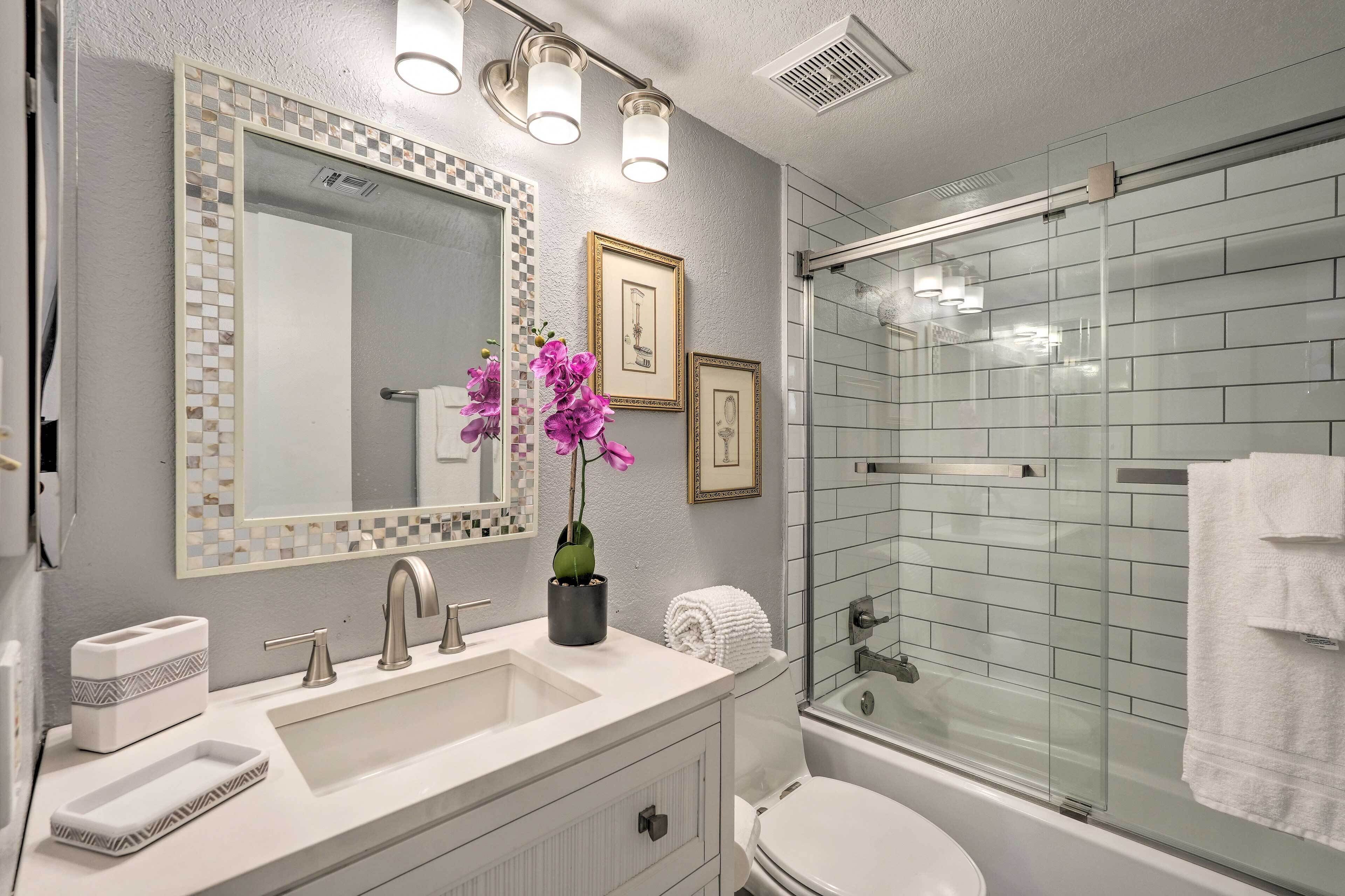 Une salle de bain moderne avec un grand miroir, un lavabo, des toilettes et une douche à parois de verre.