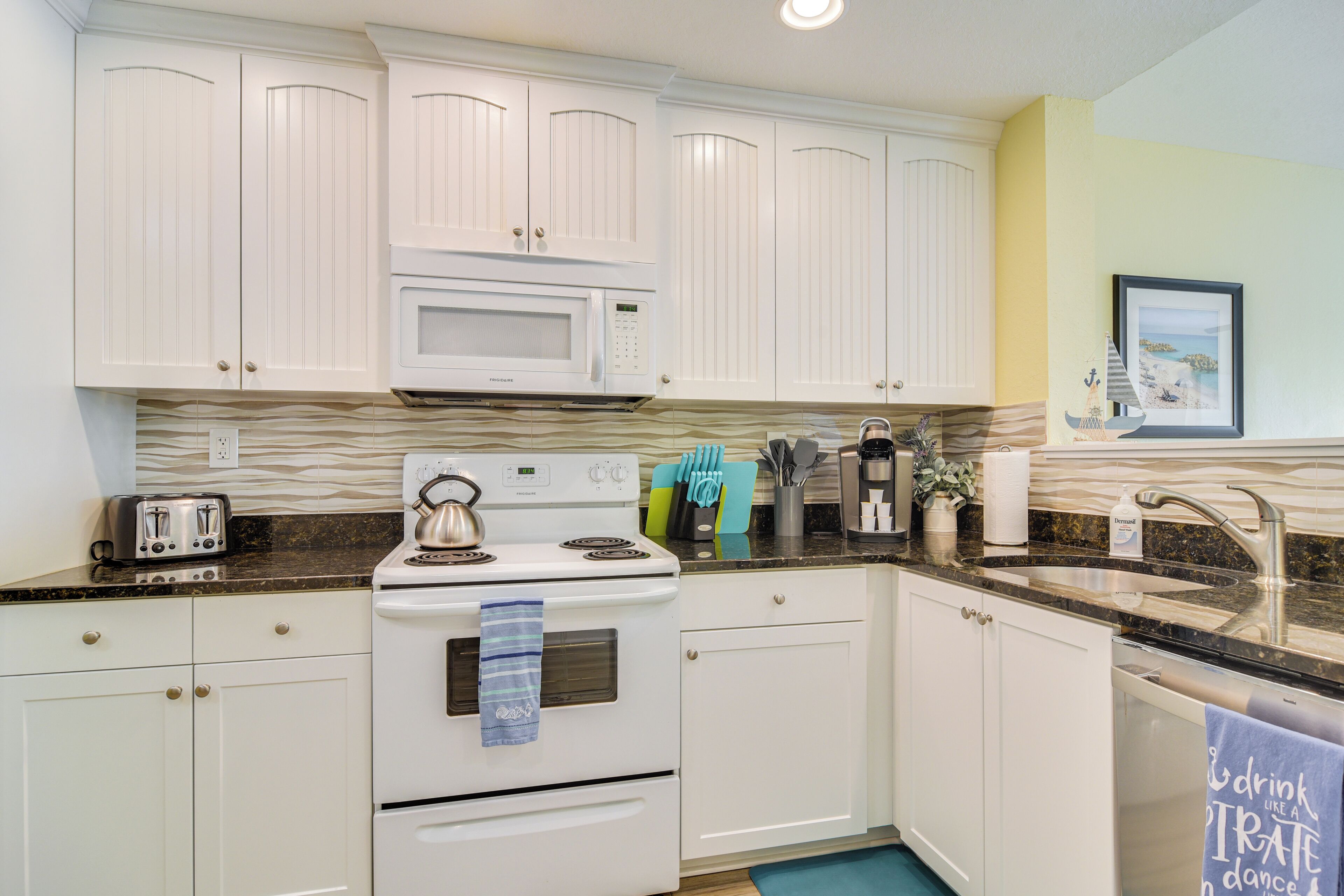 A kitchen with white cabinets, a microwave, a stove, and a sink.
