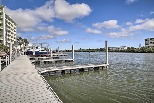 A marina with docked boats, a wooden pier, and a building with balconies.