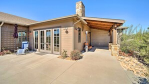 A modern house with a covered patio, large windows, and a stone chimney.
