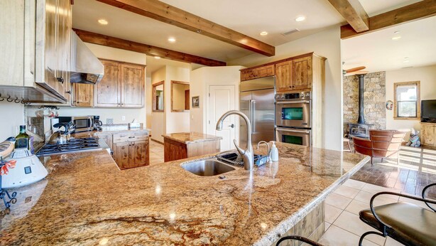 A spacious kitchen with granite countertops, stainless steel appliances, and wooden cabinets.