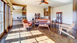 A spacious living room with a wooden floor, a ceiling fan, a leather sofa, and a coffee table.