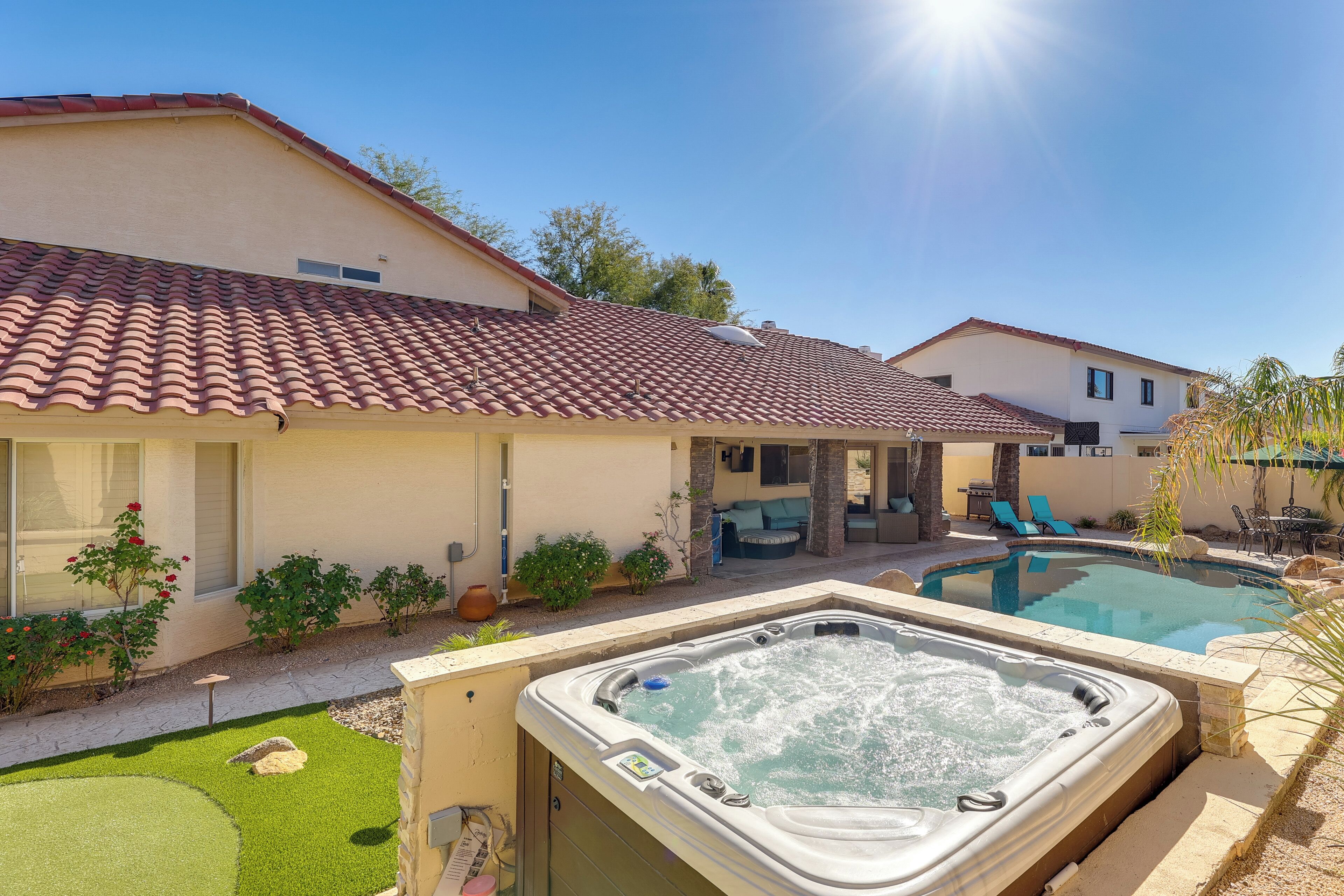 A residential property with a swimming pool, a hot tub, and a patio area with outdoor furniture.