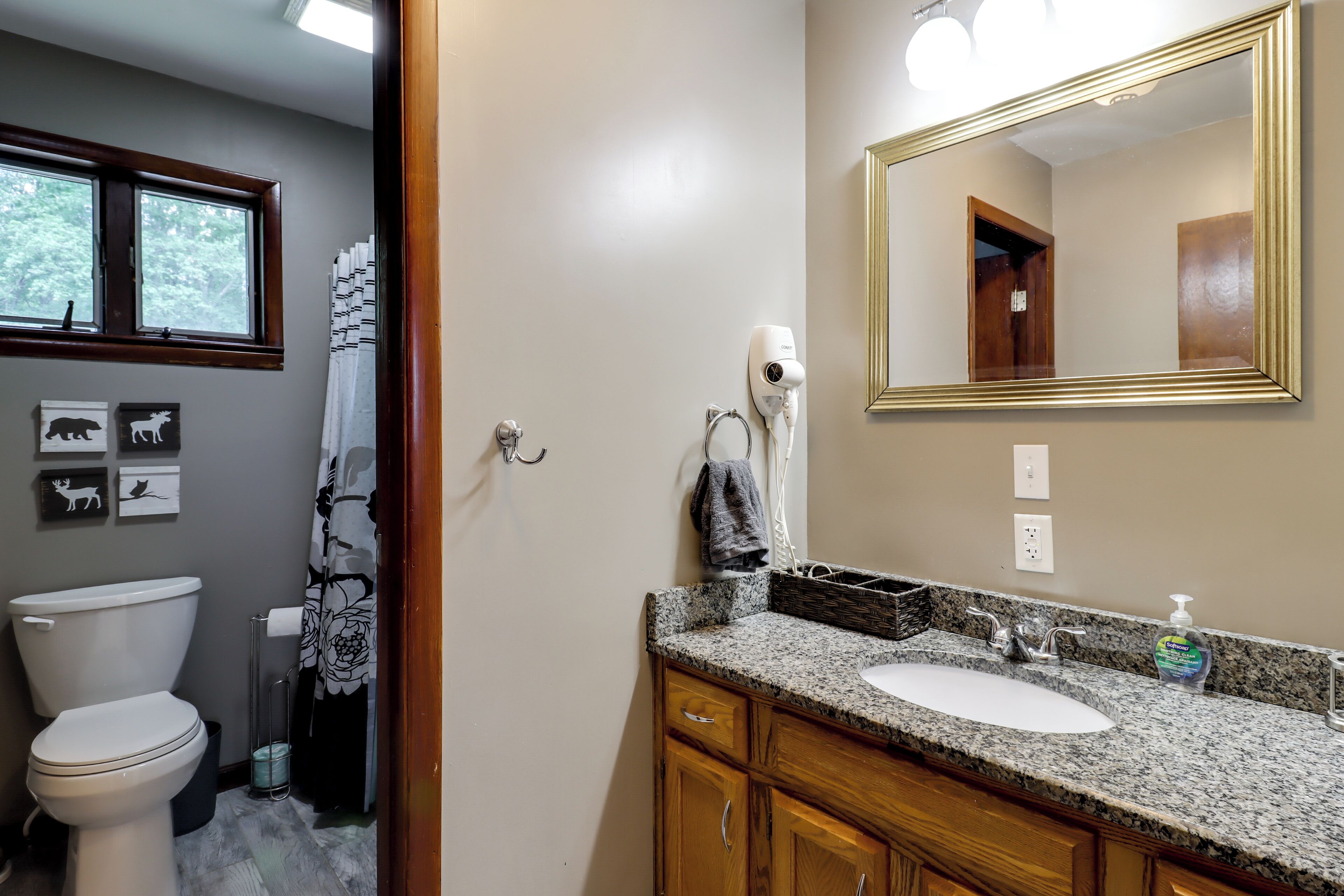 Ein Badezimmer mit Toilette, Waschbecken, Spiegel und Fön.