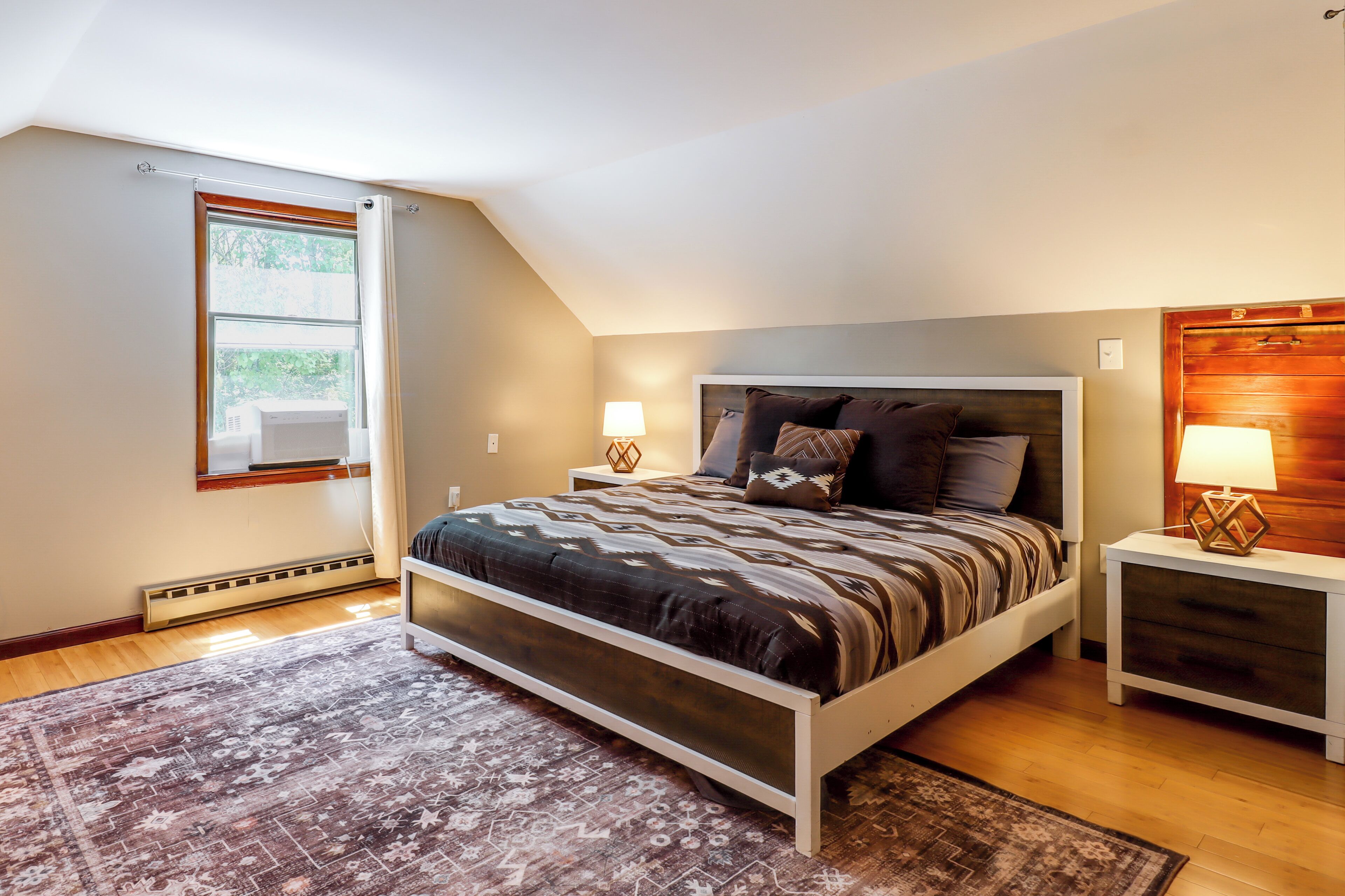 A bedroom with a bed, bedside tables, a window, and a radiator.