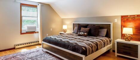 A bedroom with a bed, bedside tables, a window, and a radiator.