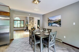 Un comedor con una mesa de madera dispuesta para seis personas, una pared de piedra y un cuadro de un paisaje montañoso.
