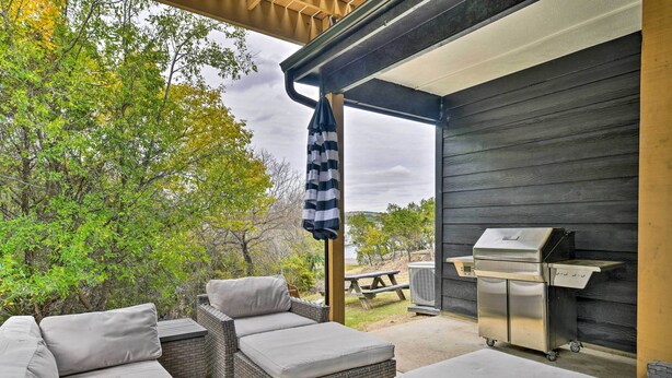 An outdoor patio with wicker furniture, a grill, and a view of trees and a lake. - Graford Cabin w/ Rooftop Deck & Lake Views! (Graford)