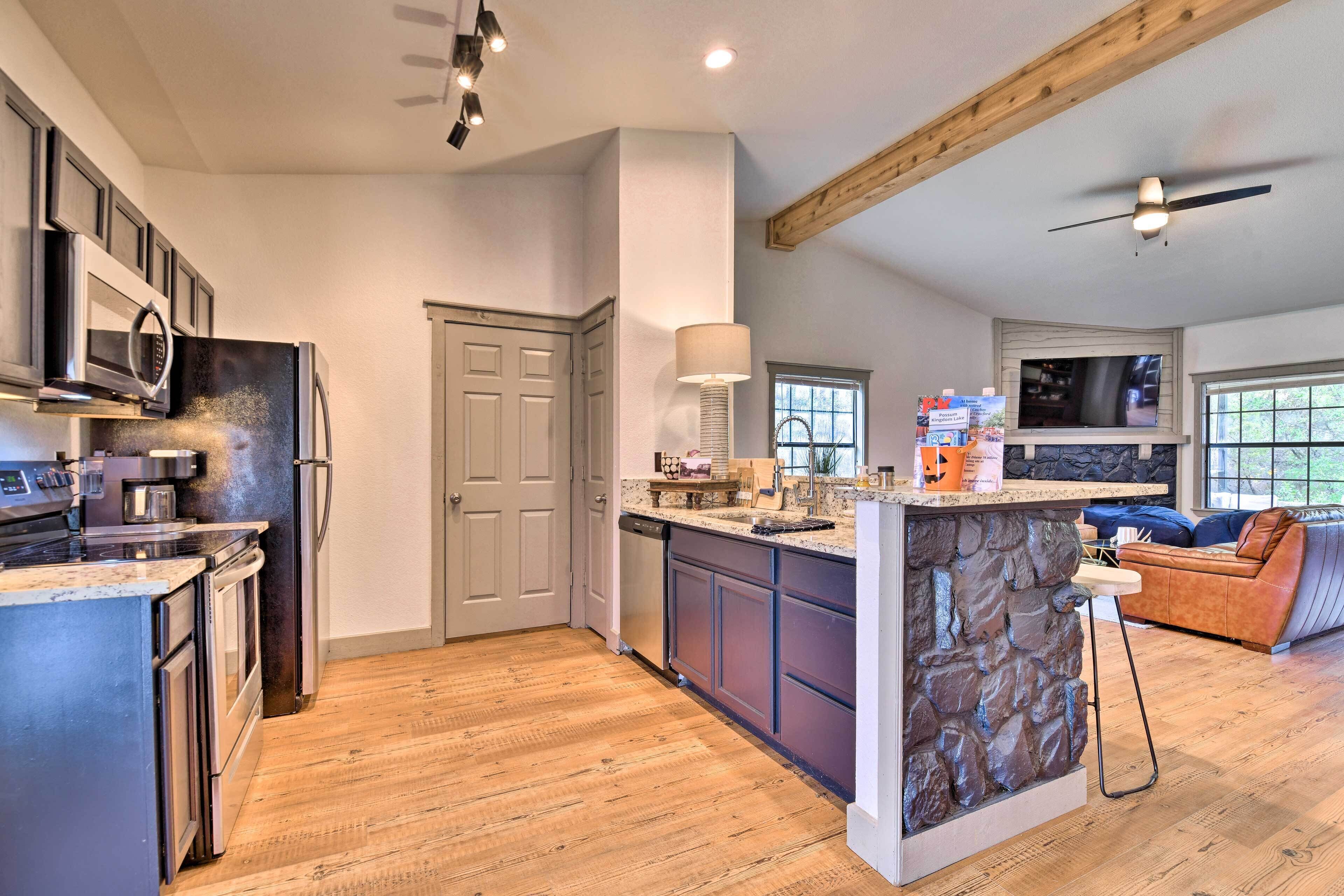 A modern kitchen with a central island, built-in appliances, and a stone accent wall.