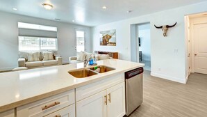 A modern kitchen with a large island, white cabinetry, and a built-in dishwasher. - 12 Mi to Dtwn Flagstaff: Spacious Bellemont Home! (Bellemont)