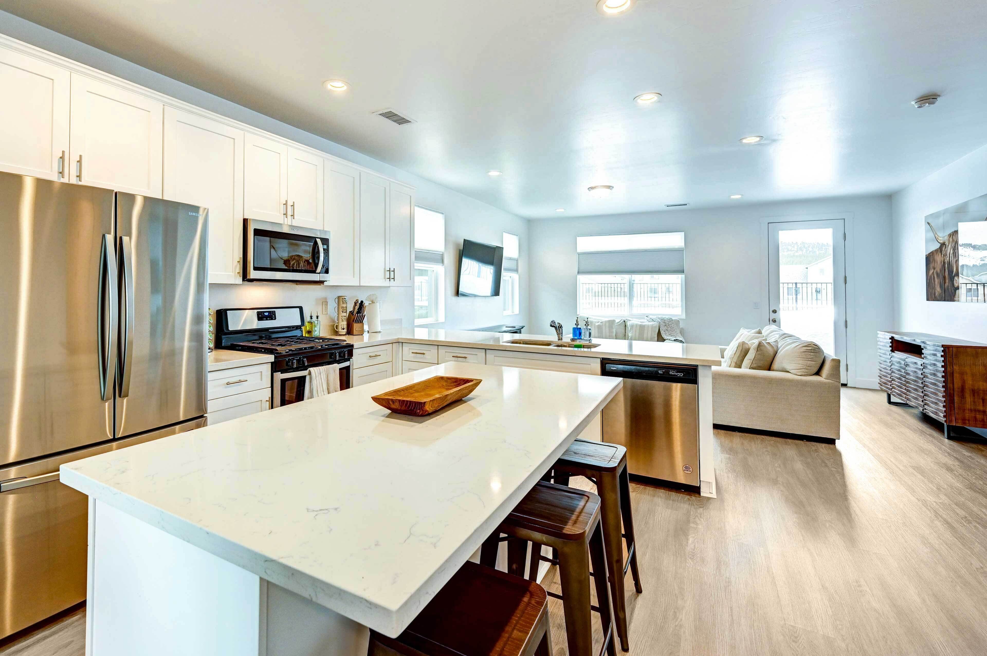 A modern kitchen with white cabinets, stainless steel appliances, and a large island.