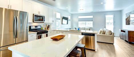 A modern kitchen with white cabinets, stainless steel appliances, and a large island.