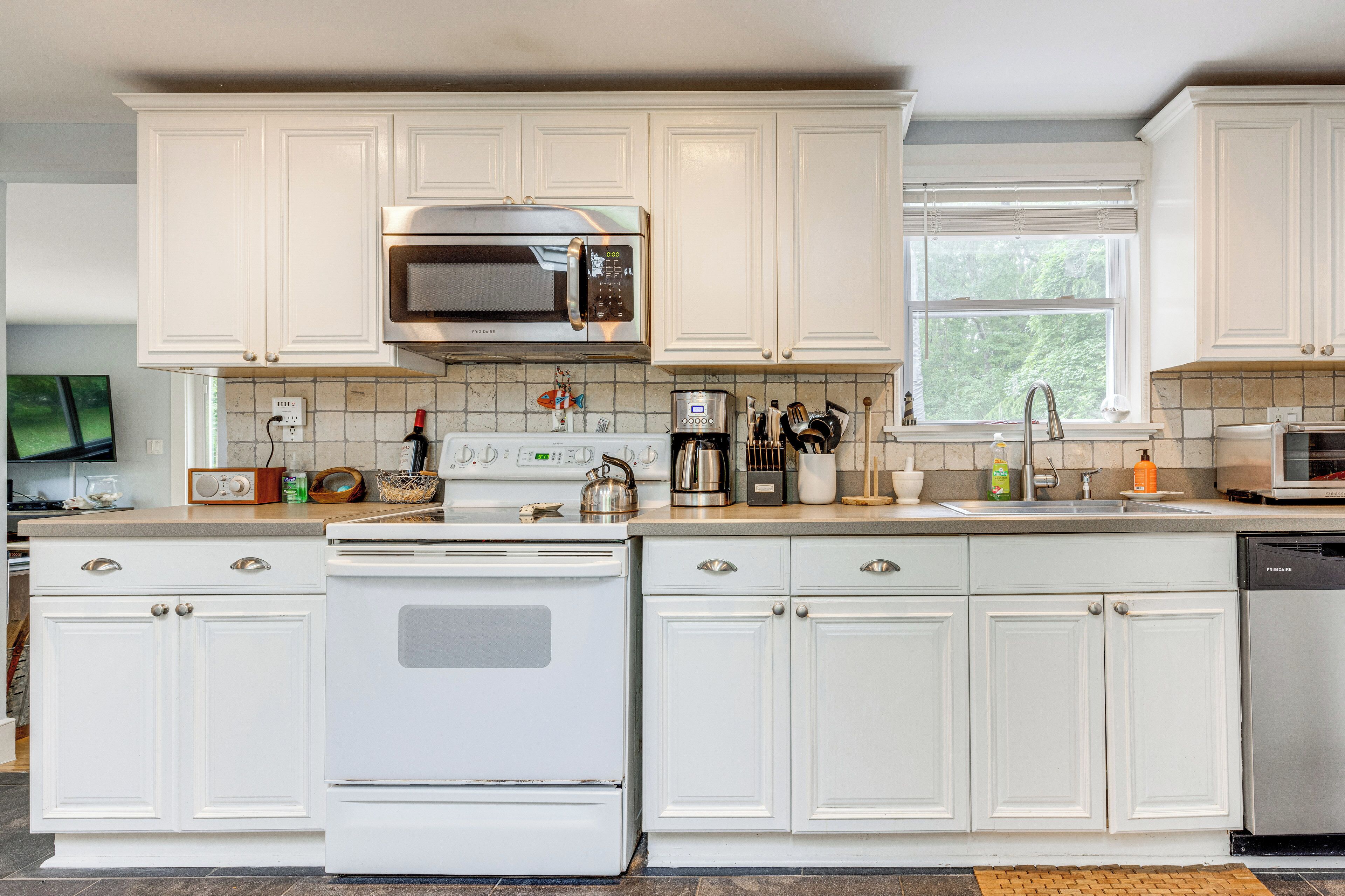 A kitchen with white cabinets, a microwave, stove, and dishwasher.