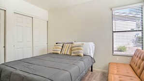 A bedroom with a bed, a window with blinds, a sofa, and a door. - Mountain-view Tucson Condo w/ Outdoor Pools! (Tucson)