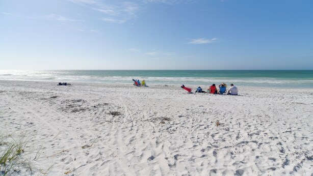 A sandy beach with people sitting and walking along the shore. - Walk to Bradenton Beach: Gulf-view Home w/ Lanai (Bradenton Beach)