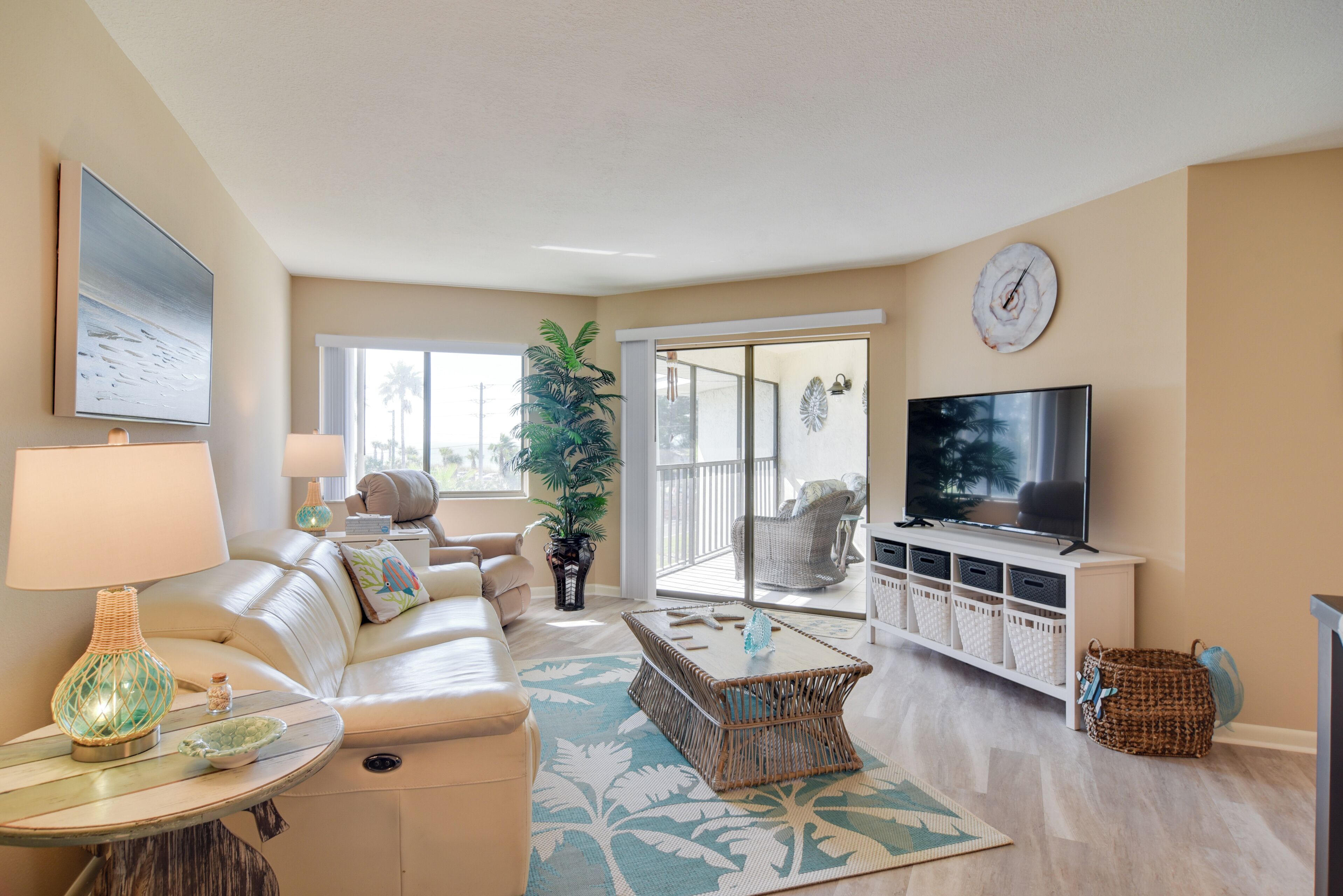 A living room with a sofa, coffee table, TV, and a balcony with a view.