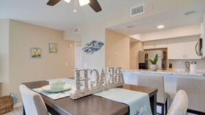 A dining area with a table set for two, a ceiling fan, and a kitchen in the background. - Walk to Bradenton Beach: Gulf-view Home w/ Lanai (Bradenton Beach)