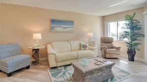 A living room with a beige sofa, a patterned armchair, a wicker coffee table, and a potted plant. - Walk to Bradenton Beach: Gulf-view Home w/ Lanai (Bradenton Beach)
