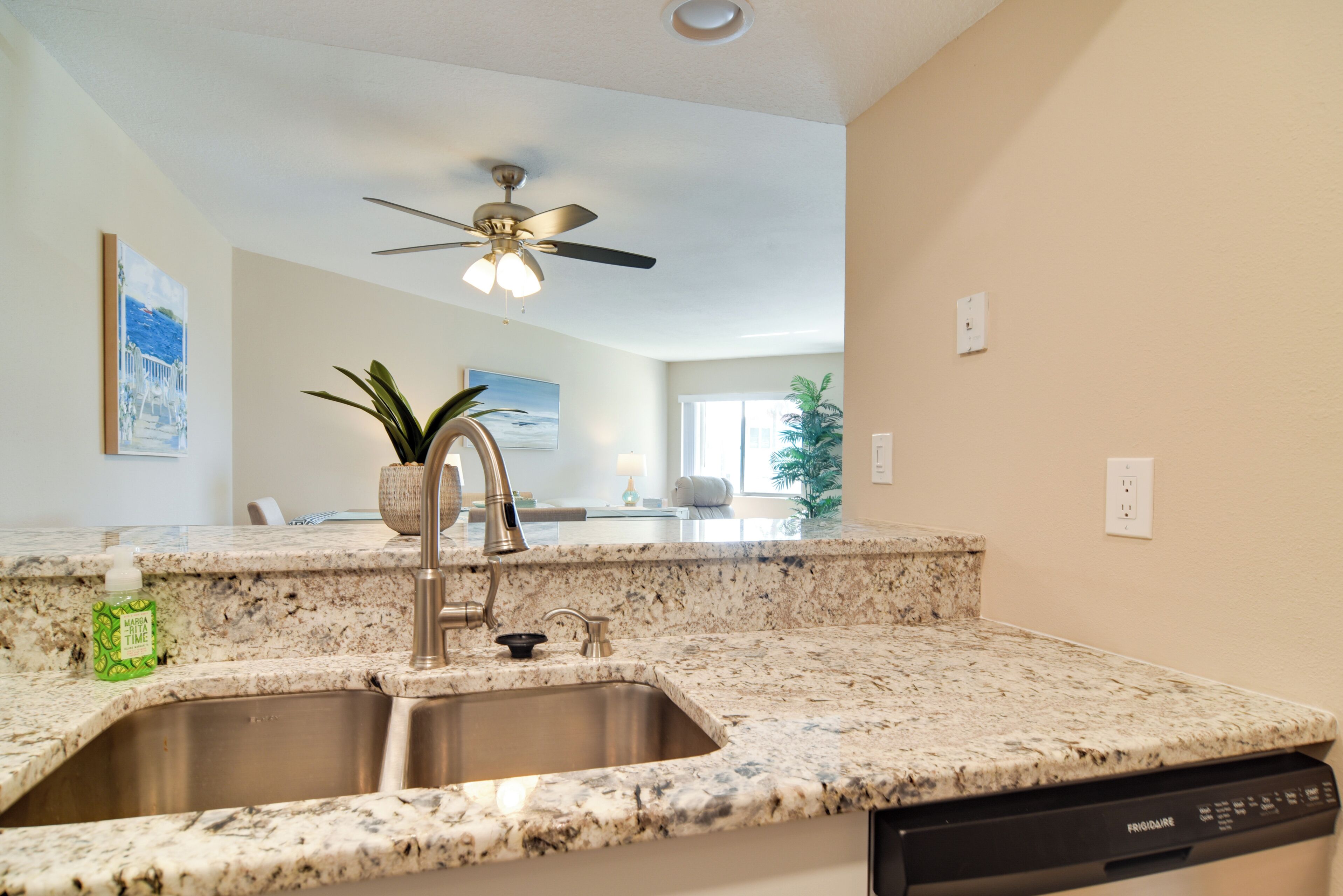 A kitchen with granite countertops, stainless steel sink, and a dishwasher.