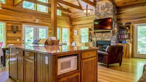 A spacious cabin with a large wooden interior, a stone fireplace, and a television mounted on the wall.