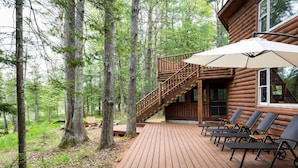A wooden deck with outdoor seating and a staircase leading to a cabin.