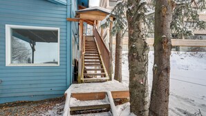 A wooden staircase leading to a blue building with a white window. - Water-view Retreat! Steps to Coastal Trail & Dtwn (Anchorage)