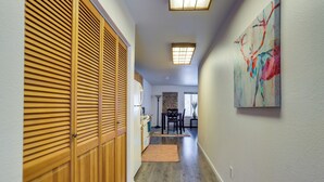 A hallway with wooden sliding doors, a dining area with a table and chairs, and a painting on the wall. - Water-view Retreat! Steps to Coastal Trail & Dtwn (Anchorage)