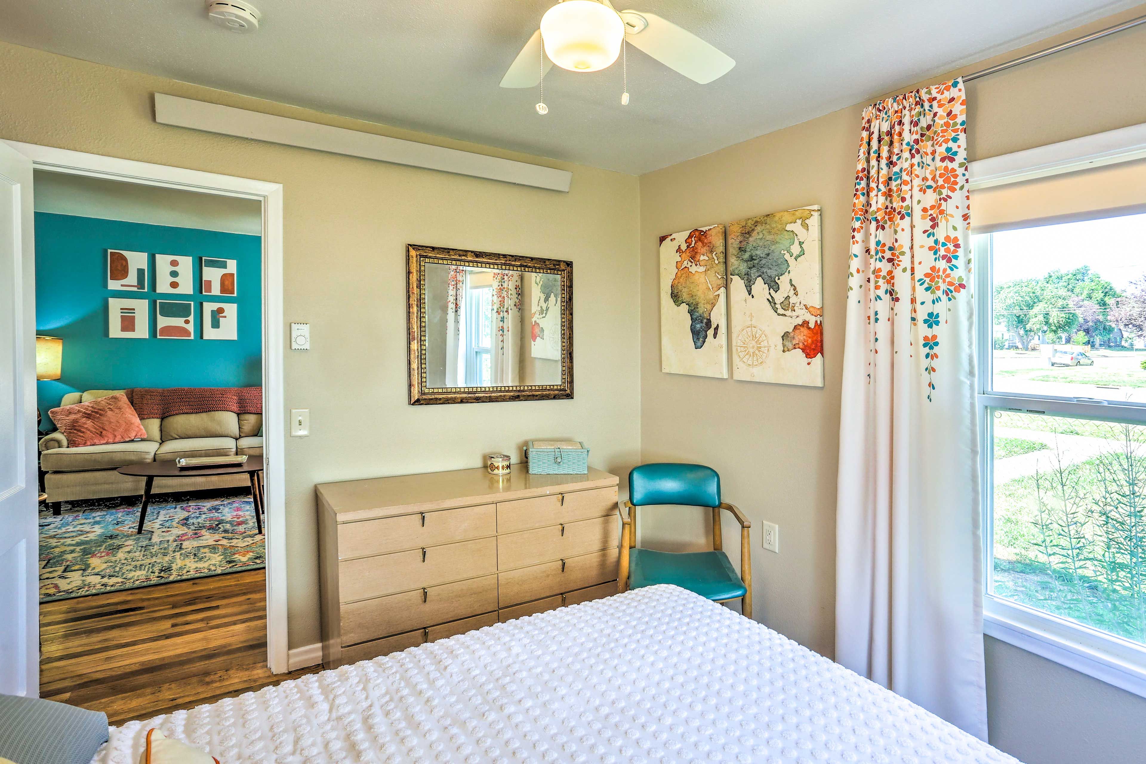 Un dormitorio con cama, cómoda, silla y una obra de arte en la pared.