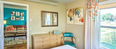 Un dormitorio con cama, cómoda, silla y una obra de arte en la pared.