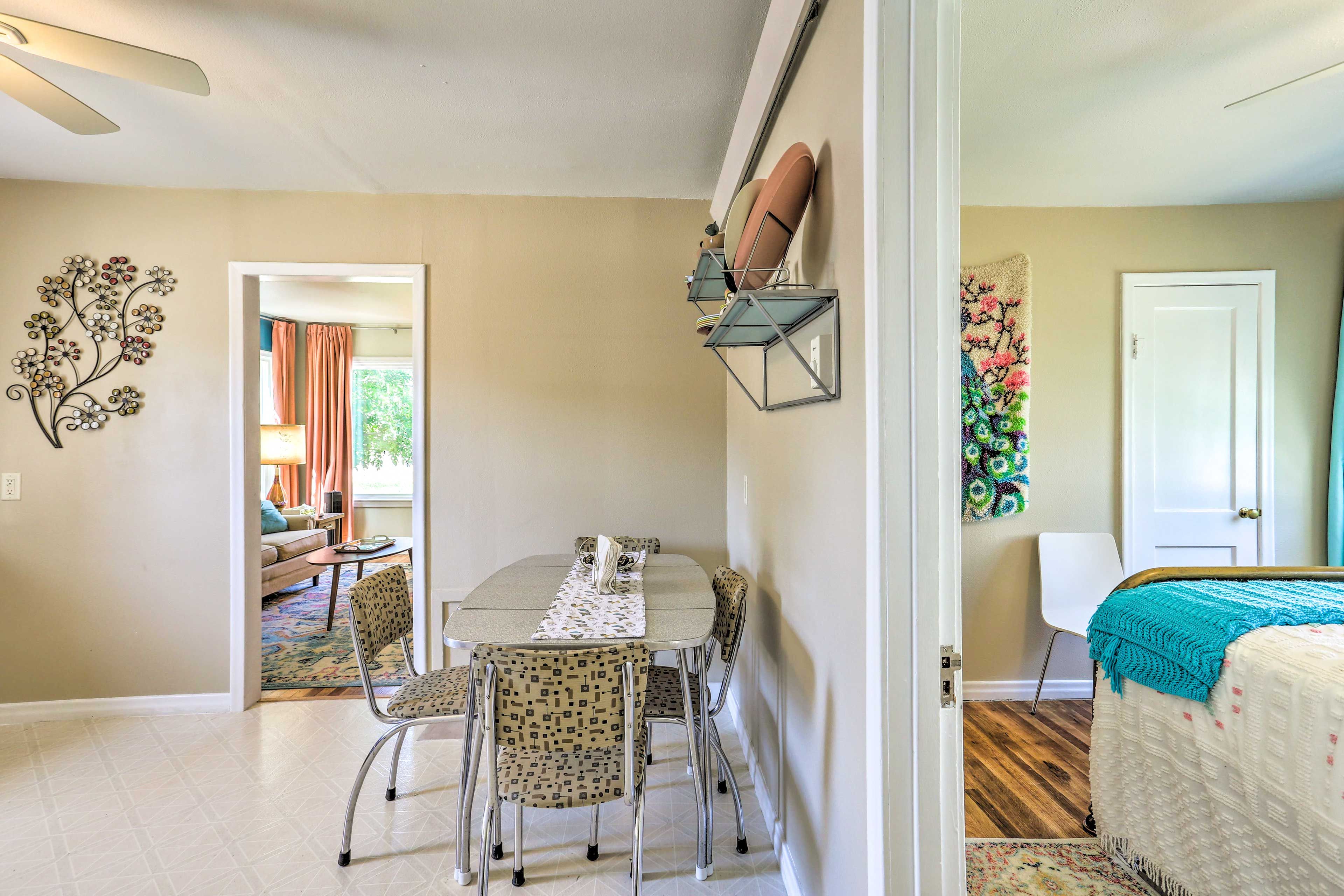 A dining area with a table and chairs, a decorative wall piece, and a door leading to another room.