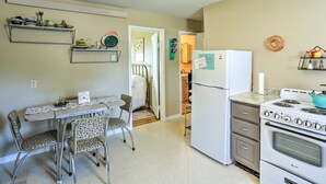 A compact kitchen with a refrigerator, stove, and dining area with chairs and a table.