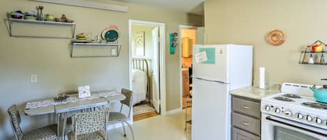 A compact kitchen with a refrigerator, stove, and dining area with chairs and a table.