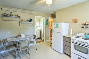 A compact kitchen with a refrigerator, stove, and dining area with chairs and a table.