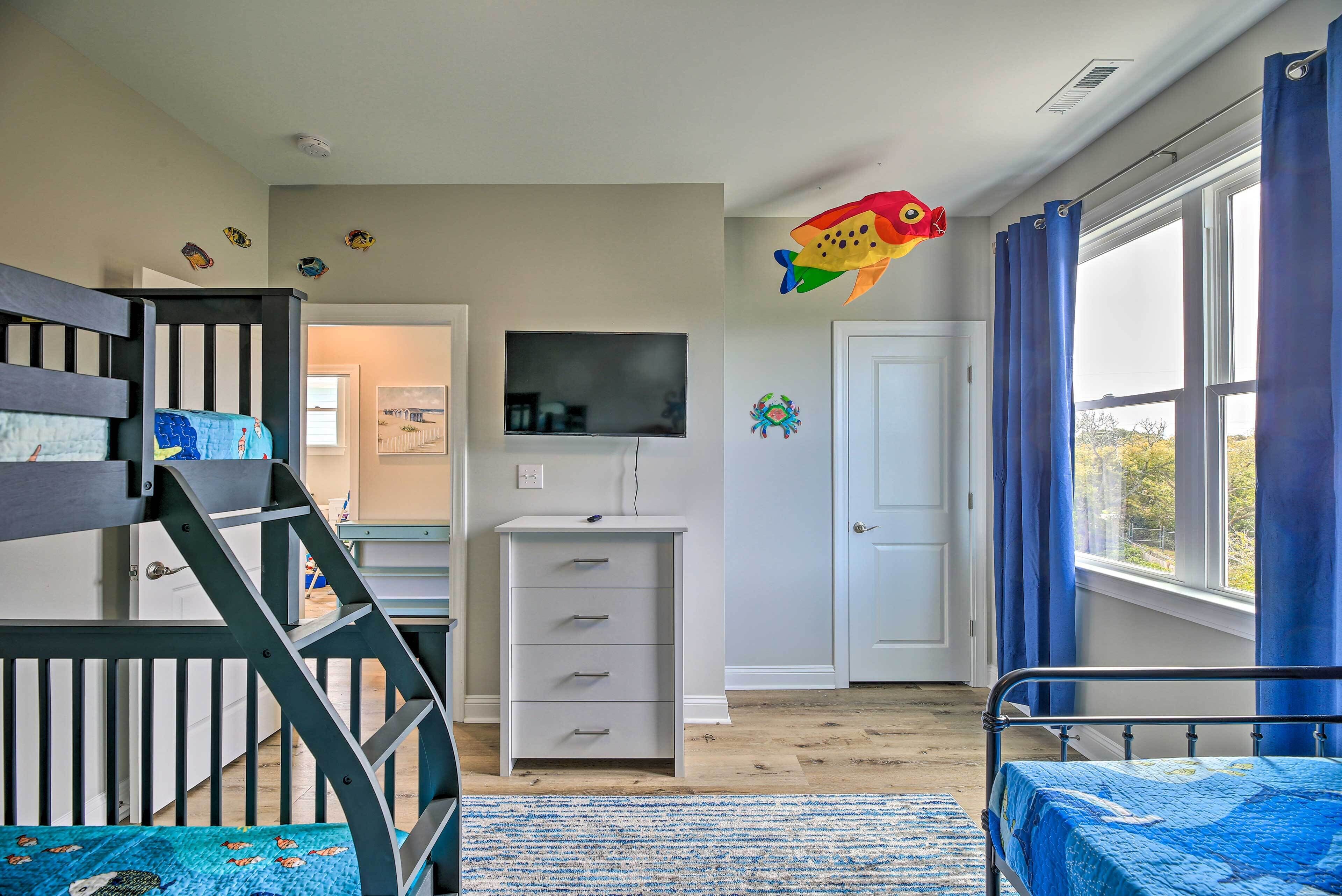 A child's room with a bunk bed, a desk, and a TV.