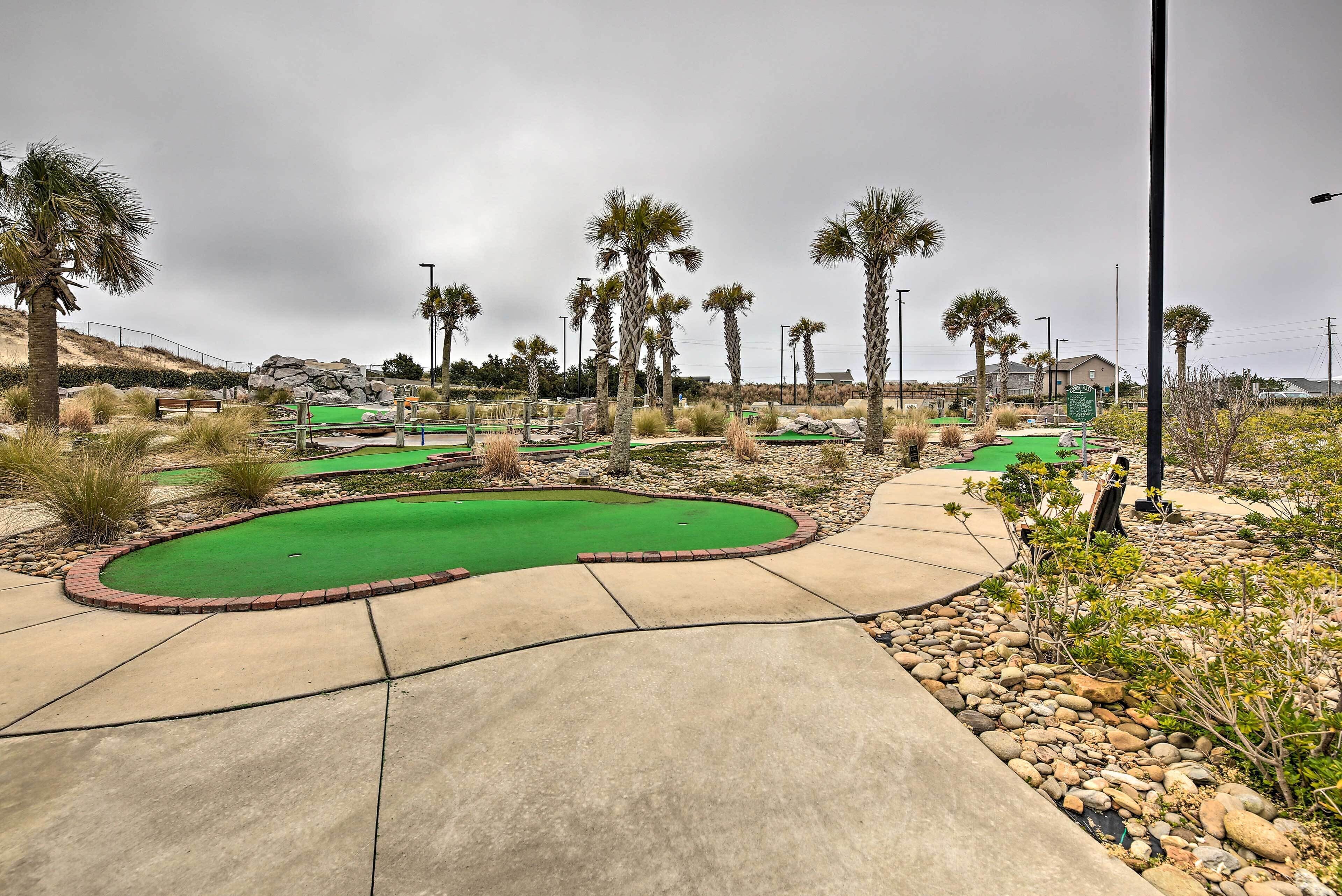 A golf course with multiple greens, palm trees, and a clear sky.