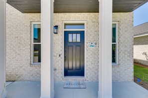 Una casa con puerta azul, felpudo y un cartel con una bicicleta.