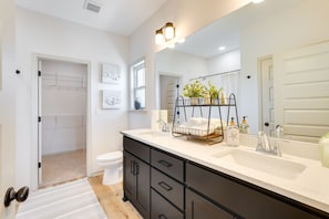 A modern bathroom with a white vanity, black cabinets, a large mirror, and a shower area. - Panama City Vacation Rental - 6 Mi to Downtown! (Panama City)