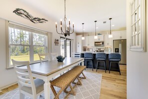 A modern kitchen with white cabinetry, a dining table with chairs, a bench, and a chandelier. - Panama City Vacation Rental - 6 Mi to Downtown! (Panama City)