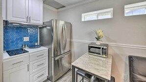 A kitchen with white cabinets, a stainless steel refrigerator, a microwave, and a marble countertop. - Cute Central Placerville Studio: Pet Friendly (Placerville)